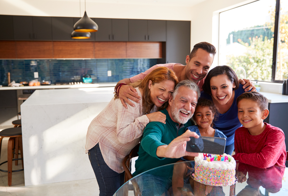 A happy multigenerational family with grandparents, parents, and a child sitting together on a sofa in a smart home environment